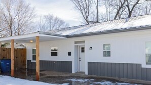 Een gelijkvloers huis met een overdekte veranda, een voordeur en een garage.