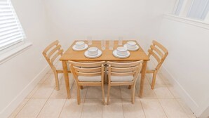 Een eettafel met zes stoelen, witte borden en glazen servies voor zes personen.