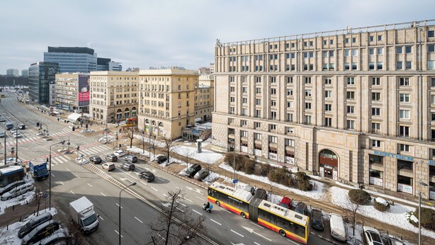Eine Stadtstraße mit Gebäuden, einem Bus und parkenden Autos.