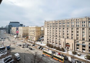 A city street with buildings, a bus, and parked cars. - Plac Politechniki Residence Apartment (Warszawa)