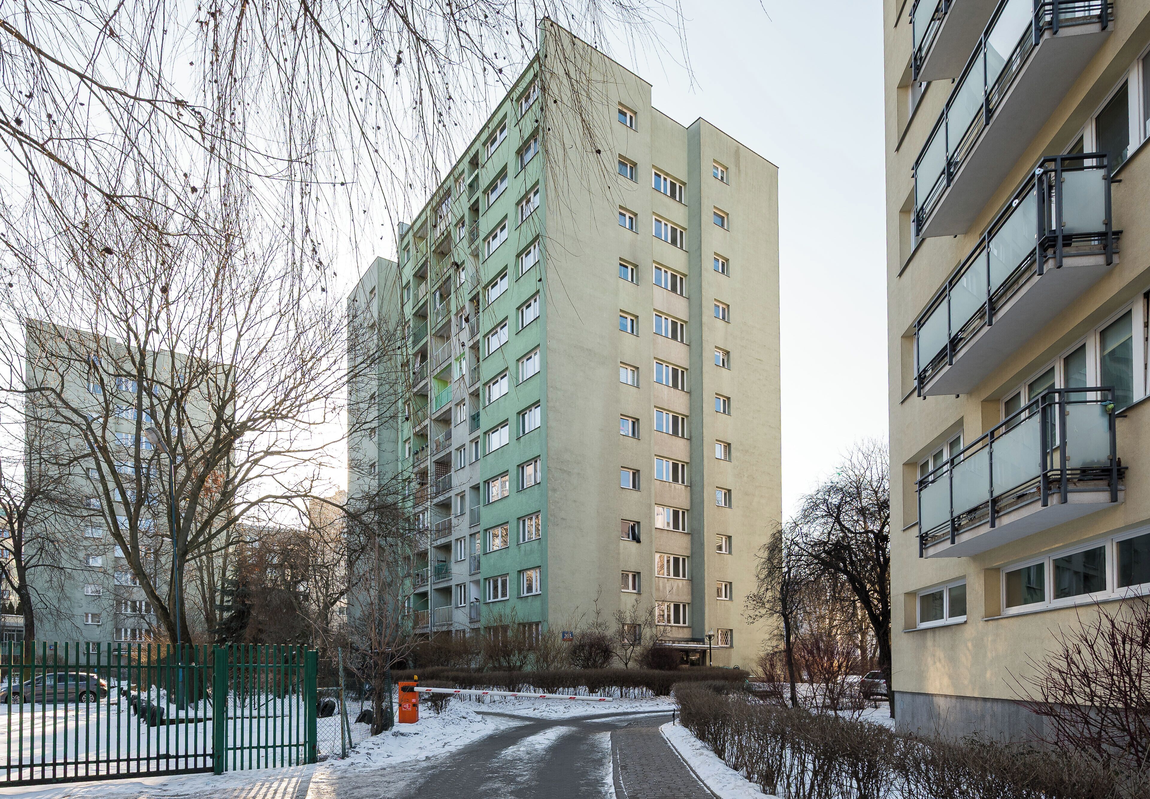 Un edificio residencial de varios pisos con balcones y una entrada portonada.