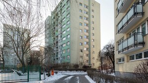 Un immeuble résidentiel à plusieurs étages, doté de balcons et d’une entrée sécurisée par un portail.