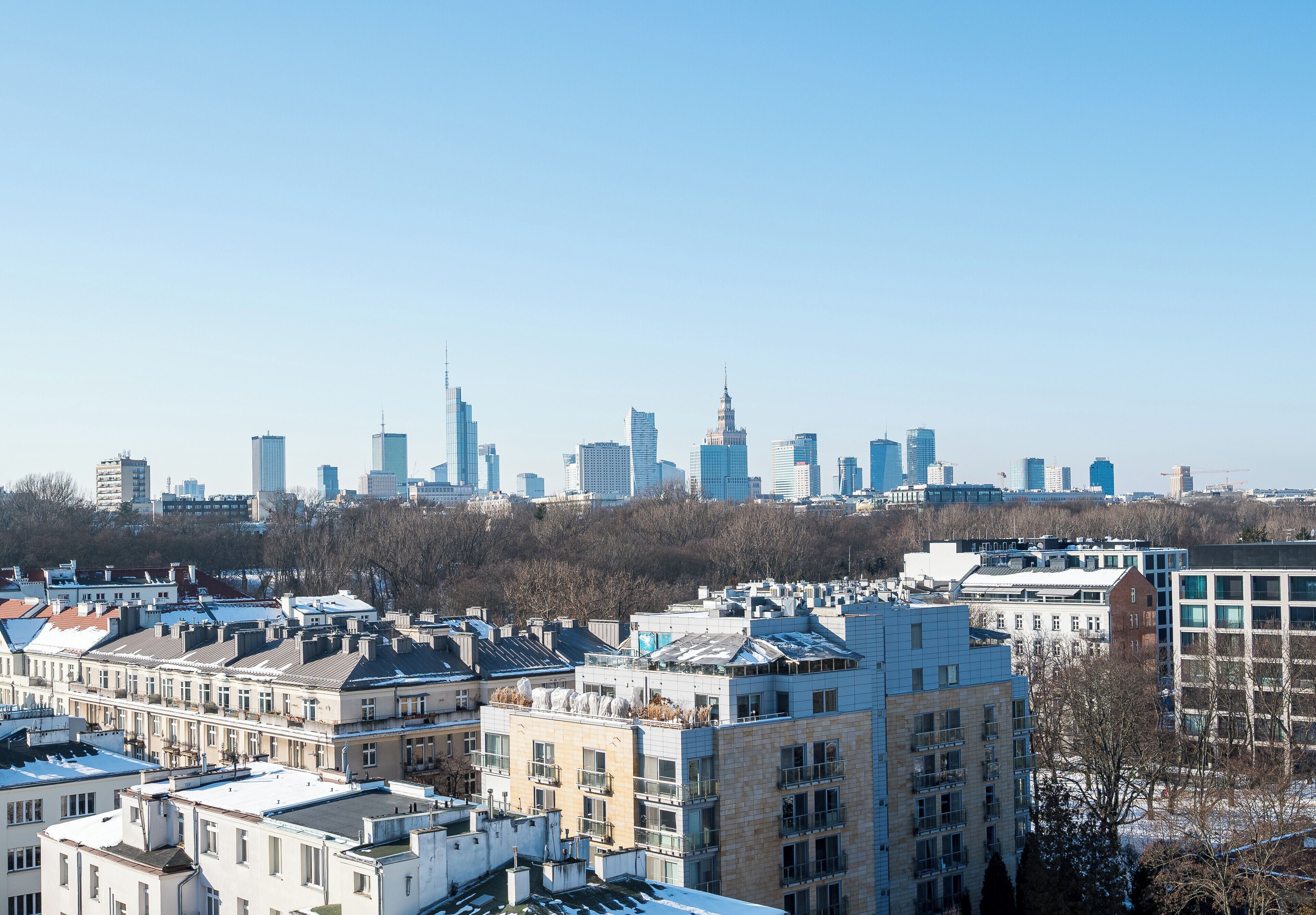 Ein Stadtbild mit modernen Hochhäusern und älteren Wohngebäuden im Vordergrund.