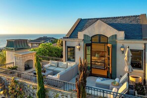 Une propriété de luxe située en bord de mer, dotée d’un vaste espace extérieur aménagé, d’une cheminée et d’une vue sur l’océan.