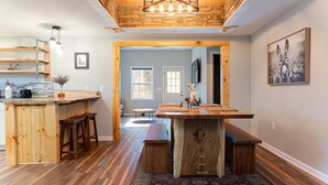 Una cocina amplia con encimeras de madera y una isla grande, un comedor con mesa de madera, y vistas a una puerta que da a otra habitación.