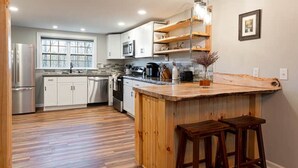 Una cocina moderna con armarios blancos, una isla de madera y taburetes de bar.