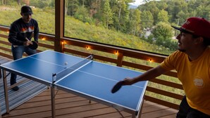 Een tafeltennistafel op een terras met uitzicht op een bebost gebied.