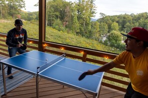 A ping pong table on an outdoor deck with a view of a forested area. - Blue Mountain Cottage | 3BR, 2BA mountain-view retreat with fireplace. (Fairview)