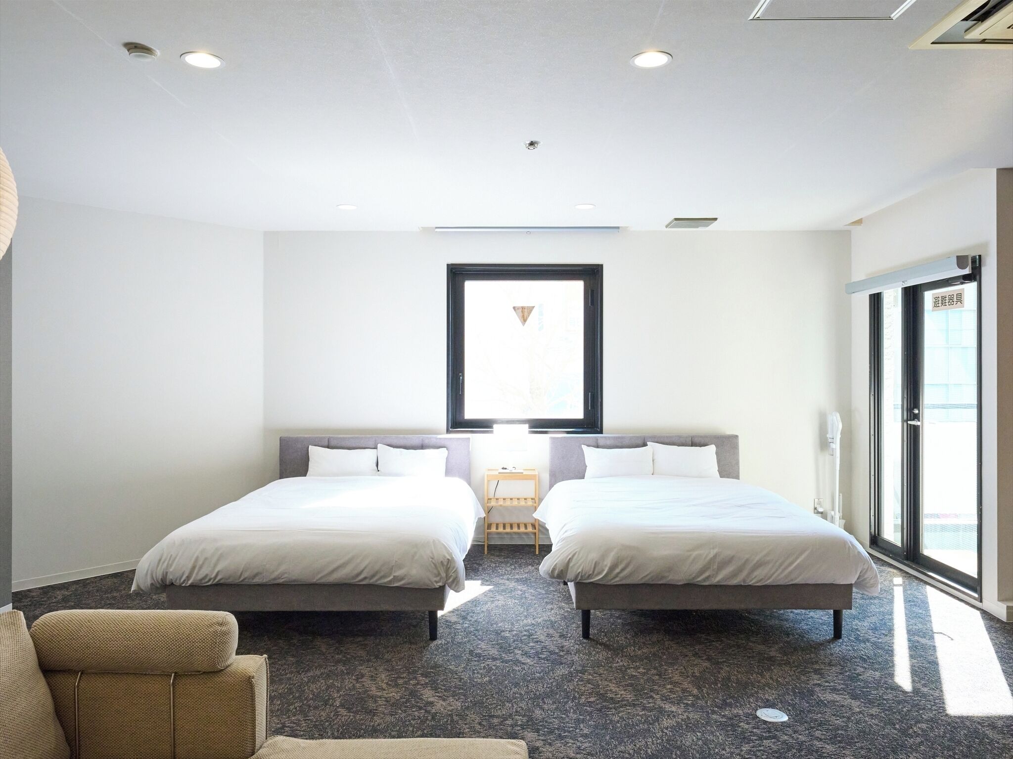 A hotel room with two beds, a large window, and a view of the city.
