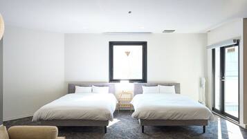 A hotel room with two beds, a large window, and a view of the city.