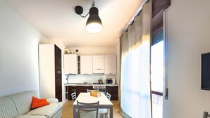A compact living space with a dining area, kitchenette, and a sofa with orange cushions.