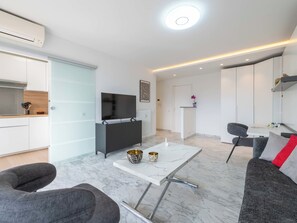 A modern living room with a flat-screen TV, a marble coffee table, and a sofa. - Studio in a Prestigious Residence, Close to the City Centre (Cannes)