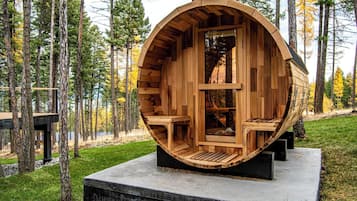 A wooden cabin with a curved exterior, built into a forest setting.