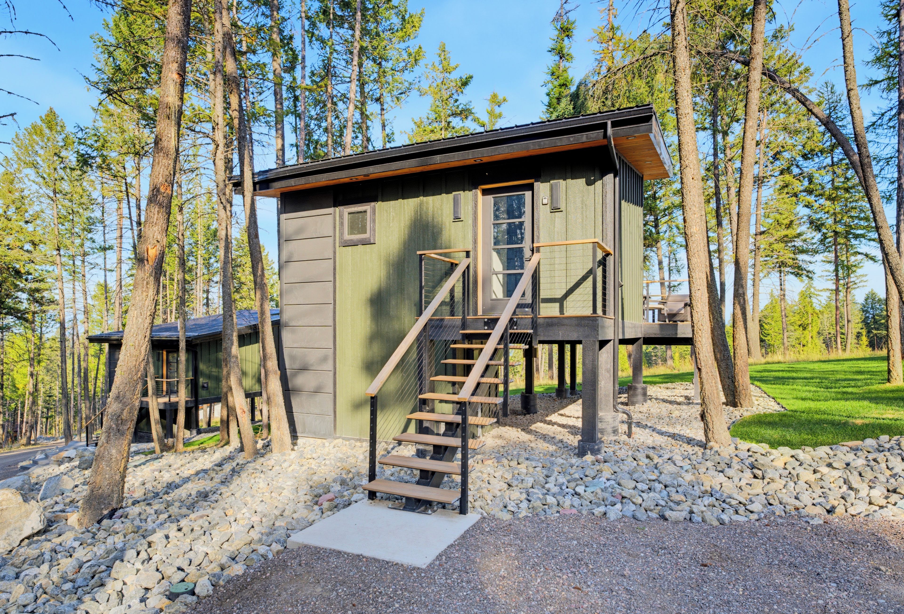 Een chalet met een houten trap die uitkomt op een terras, omgeven door bomen.