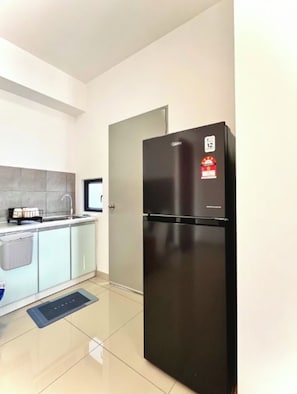 A modern kitchen with a black refrigerator, a sink, and a countertop with a dish rack. - 4BR KL Skyline View! 8-10 pax, 2 Bath, Iconic Towers (Cheras)