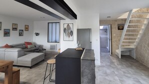A modern living room with a grey sofa, a black coffee table, and a staircase leading to an upper level. - Charming house between the countryside and the sea (SAINT NAZAIRE SUR CHARENTE)