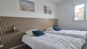 A hotel room with two beds, a wooden slat headboard, and two wall-mounted paintings. - Charming house between the countryside and the sea (SAINT NAZAIRE SUR CHARENTE)