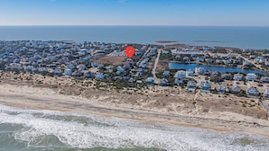 Luchtbeeld van een kustgebied met woonhuizen, een strand en een wateroppervlak.