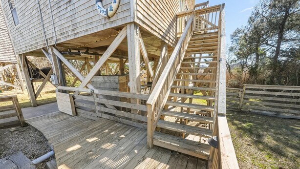 Een houten terras met een trap naar een overdekt gedeelte.