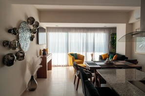 Ein modernes Wohnzimmer mit Essbereich, ausgestattet mit einer Couch, Sesseln, einem Couchtisch und einer Wanddekoration.