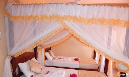 A room with a canopy bed, two bedside tables, and a small sitting area.
