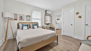 Een slaapkamer met een houten bed, een staande lamp, een bureau en een stoel.