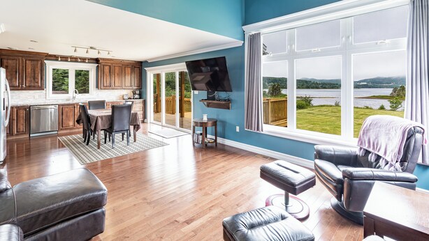 Een ruime woonkamer met een groot raam met uitzicht op een meer en bergen.