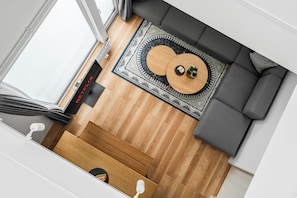 Un salon moderne avec un canapé gris, une table basse en bois et un tapis à motifs.