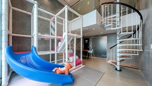 A play area with a blue slide, a climbing structure, and a spiral staircase. - Geoje Rainbow Kids Pool Villa (Geoje)