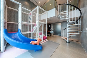 A play area with a blue slide, a climbing structure, and a spiral staircase. - Geoje Rainbow Kids Pool Villa (Geoje)