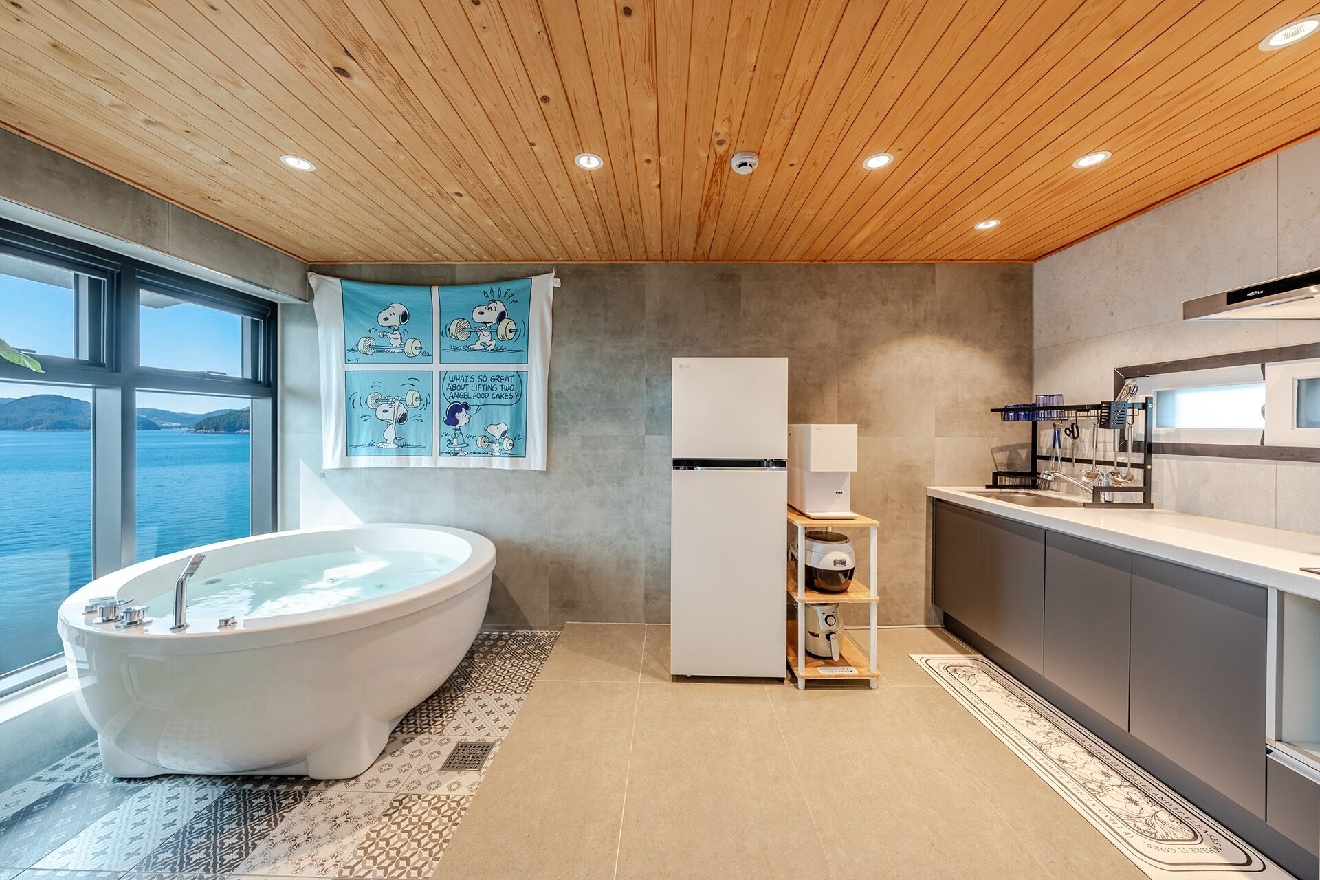 Un baño moderno con una bañera independiente, un inodoro empotrado y un amplio ventanal con vistas al mar.