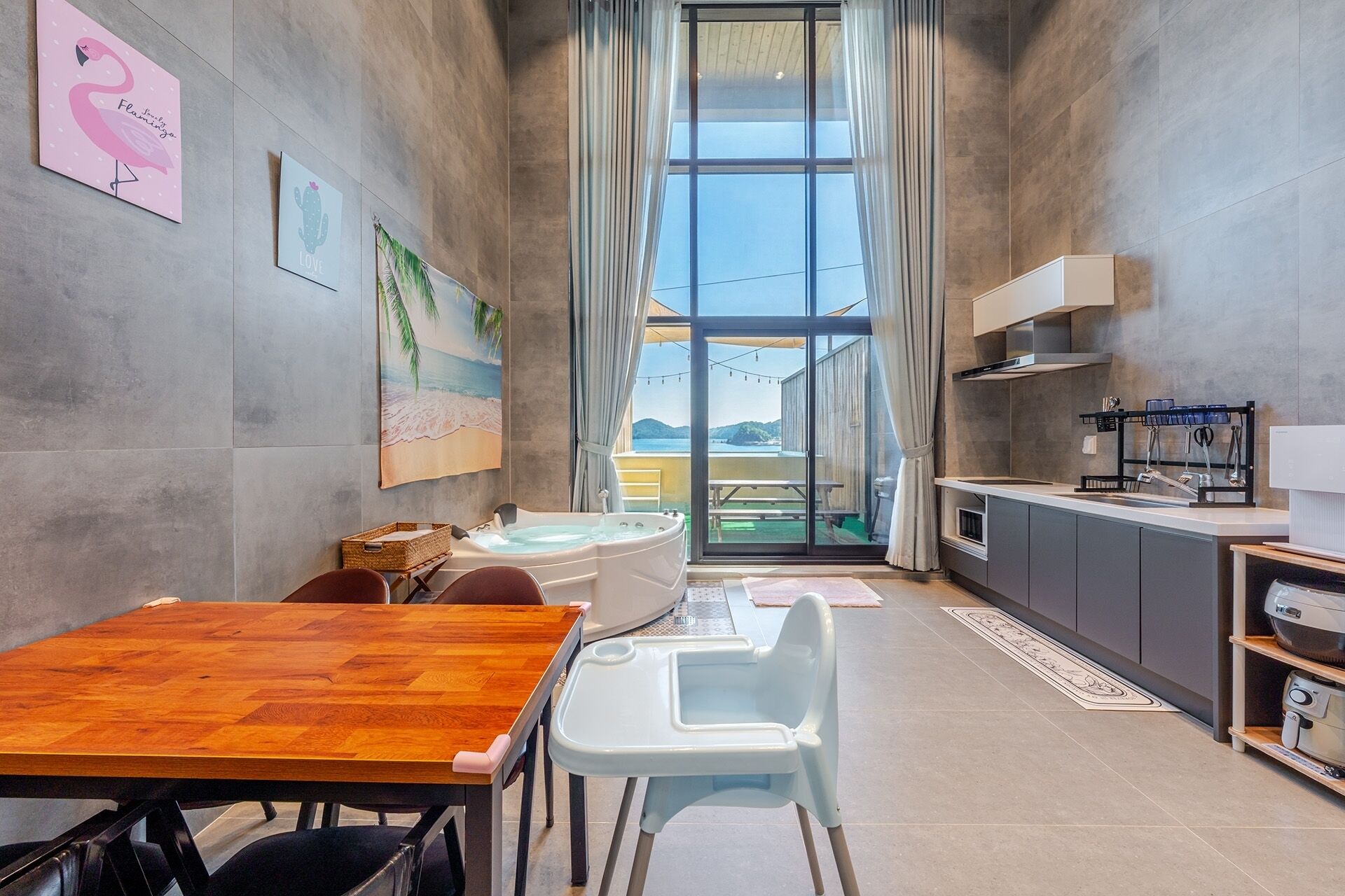 A compact kitchen with a dining area, a view through a large window, and a wooden table.