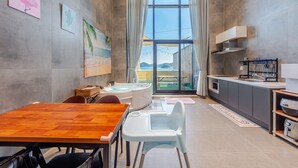 Cuina compacta amb zona de menjador, vista per una finestra gran i taula de fusta.