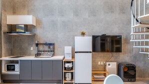 A modern kitchen with a built-in microwave, a refrigerator, a TV, and a mini fridge. - Geoje Rainbow Kids Pool Villa (Geoje)
