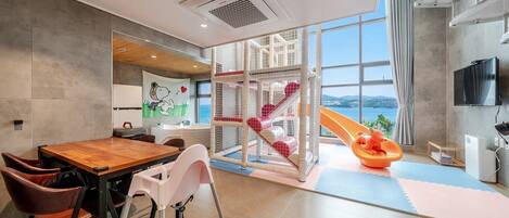 Un interior moderno con zona de comedor, estructura de juegos y un ventanal con vistas.