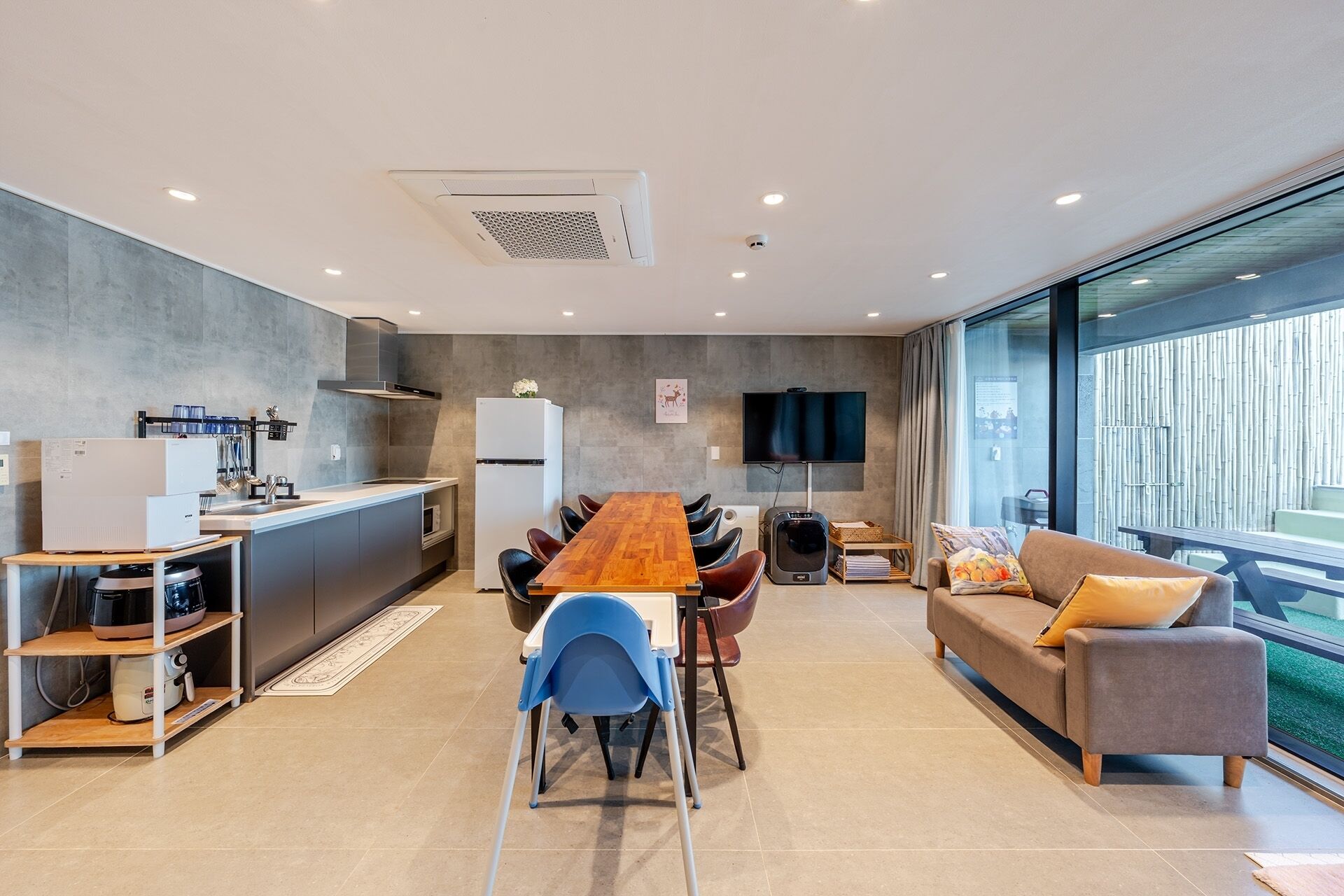 A modern kitchen with a dining area, a sofa, and a TV.