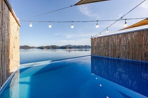 A pool with clear blue water, surrounded by bamboo walls and a wooden deck. - Geoje Rainbow Kids Pool Villa (Geoje)