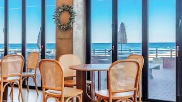Vista costera desde un restaurante con sillas de mimbre y una mesa de madera.