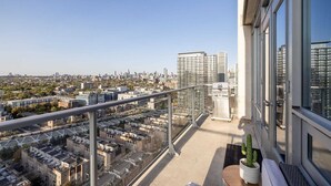Een balkon met uitzicht op de stad, een cactus in een pot en een kleine tafel.