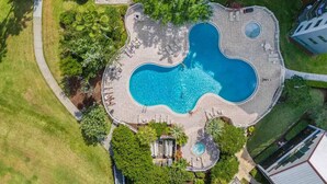 Vue aérienne d’un complexe hôtelier doté d’une piscine centrale, entourée d’espaces de détente et de verdure.