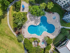 An aerial view of a resort with a central swimming pool, surrounded by lounge areas and greenery. - Unique & glamorous Universal studio (Orlando)