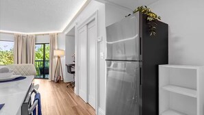 Une cuisine moderne dotée d’un réfrigérateur en acier inoxydable, d’une table à manger avec des chaises et offrant une vue sur l’extérieur.