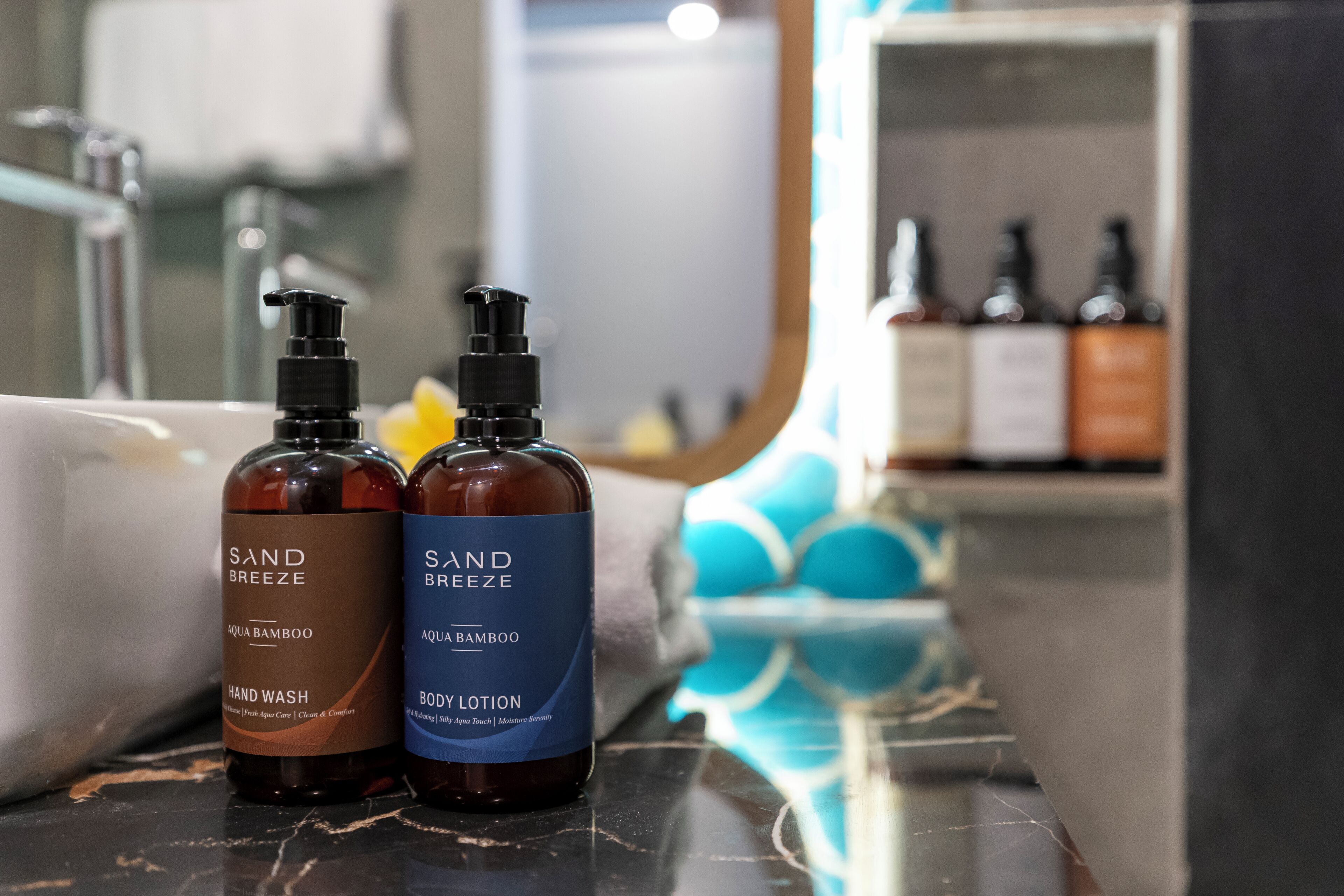 Dos botellas de productos Sand Breeze, un jabón de manos y una loción corporal, sobre un mueble de baño.