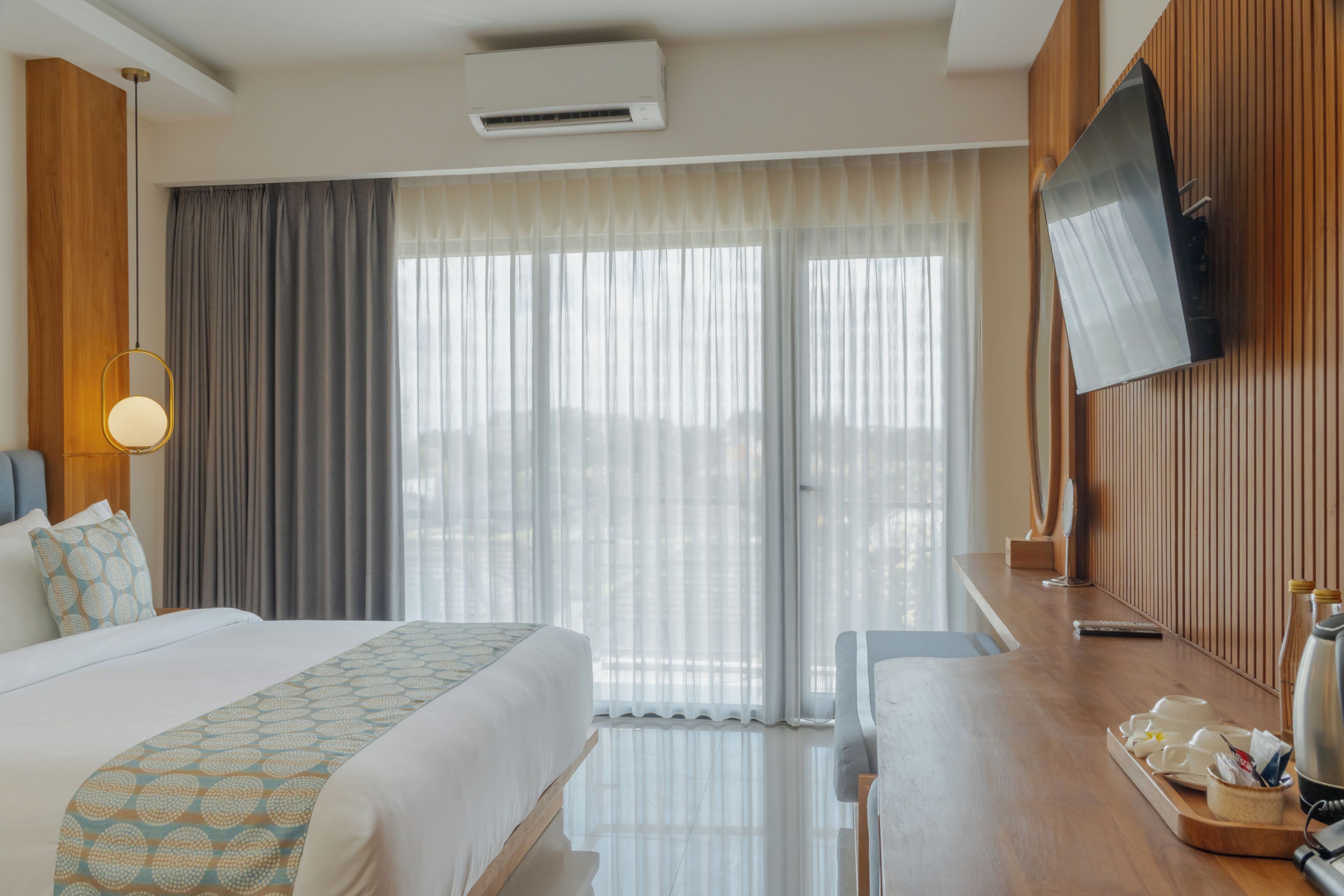 A hotel room with a bed, a desk, a TV, and a window with curtains.
