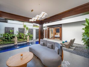 A modern outdoor living area with a pool, a sofa, and a table. - THE SAND Suites & Villas (Jimbaran)