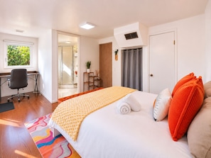 Ein Hotelzimmer mit Bett, Schreibtisch, Stuhl, Dusche und Blick auf Grünflächen.