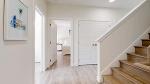 A hallway with a wooden staircase, white doors, and a framed picture on the wall. - Shared Heated Pool, Pickleball Court, Pet Friendly, Golf Cart Access (Port Aransas)