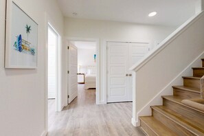 A hallway with a wooden staircase, white doors, and a framed picture on the wall. - Shared Heated Pool, Pickleball Court, Pet Friendly, Golf Cart Access (Port Aransas)