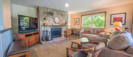 A cozy living room with a stone fireplace, a television, and comfortable seating.