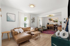 Ein modernes Wohnzimmer mit einer Ledersofa, einem Holztisch und einem Essbereich mit Holzschrank und Stühlen.